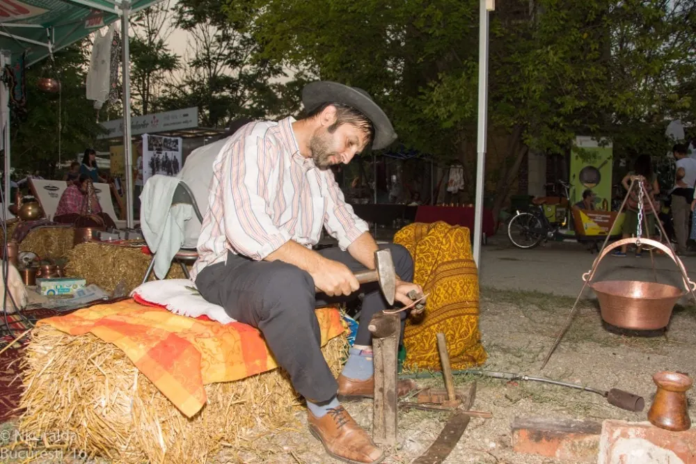 Meșter rom cu pălărie lucrând la o nicovală, la Balkanik Festival 2016
