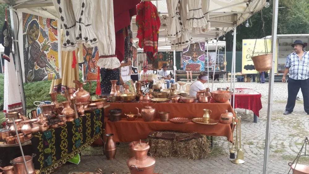 Obiecte din cupru și costume tradiționale expuse sub cort
