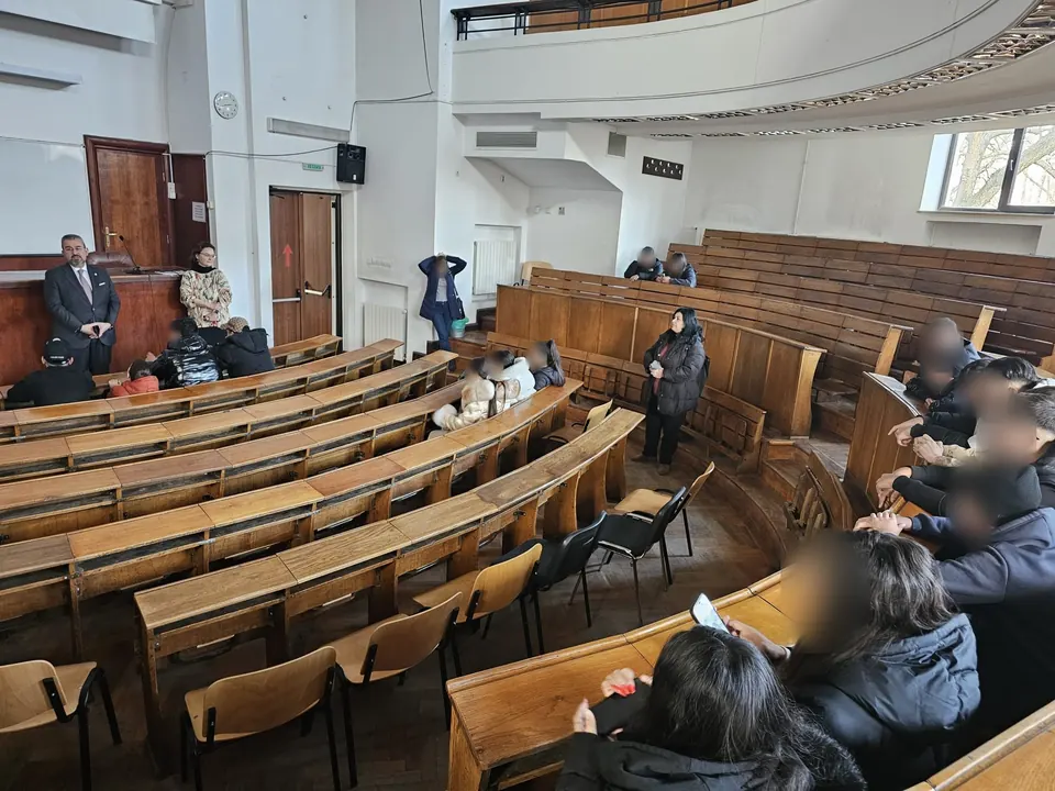 Elevi și profesori într-un amfiteatru cu bănci din lemn