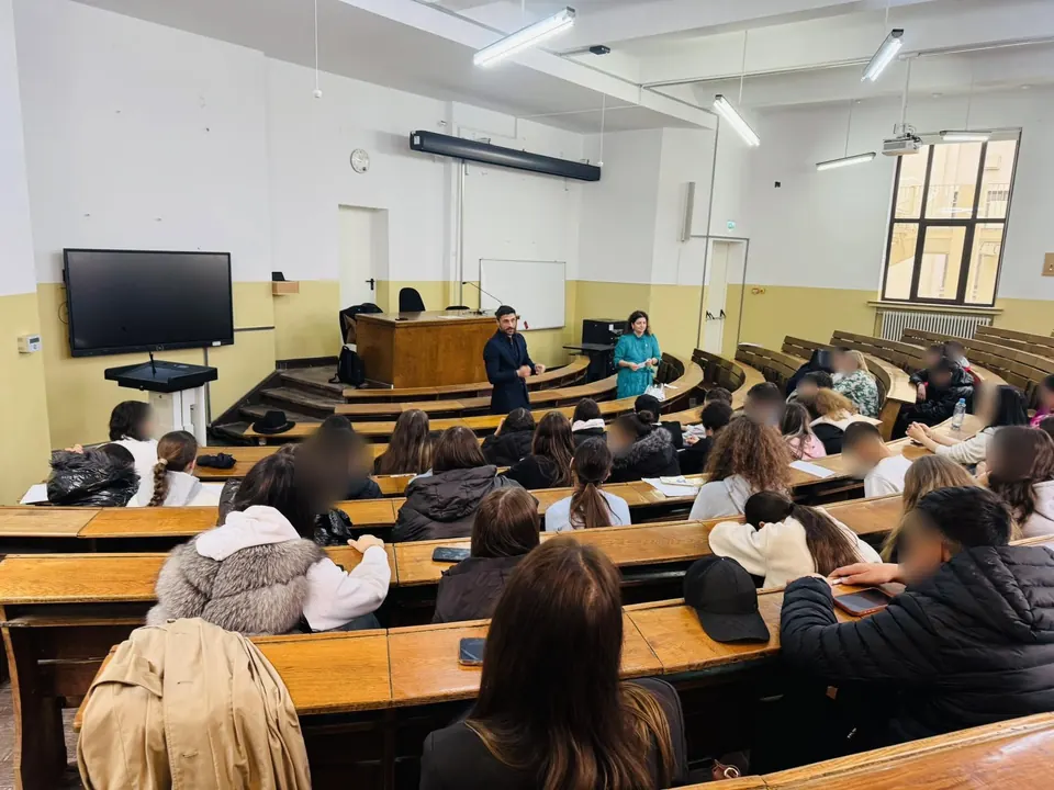 Elevi de clasa a VIII-a într-un amfiteatru al Facultății de Drept, ascultându-i pe cei doi invitați