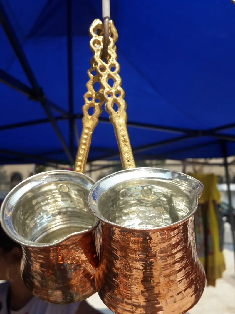 Copper coffee pots hanging under a blue tent
