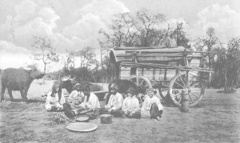 Historical photograph: a Roma family beside a covered wagon