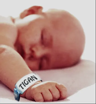 Bebeluș care doarme, cu o brățară de spital pe care scrie „ȚIGAN”