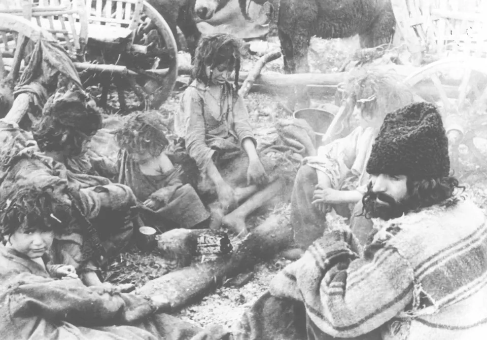 Fotografie istorică alb-negru: o familie de romi adunată în jurul focului